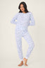 Woman wearing light blue pajamas with a subtle pattern on a white background